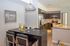 Modern kitchen and dining area with sleek dark wood cabinets, stainless steel appliances, and inviting decor setting a cozy and stylish ambiance.