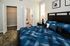 Inviting bedroom with plush blue bedding, modern decor, and an adjoining bathroom with white cabinetry and accents.