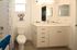 Bright and modern bathroom featuring sleek cabinetry, playful shower curtain, and stylish wall art.