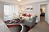 Inviting living room with modern decor, featuring a cozy white sofa, vibrant red and gray accents, and stylish artwork.