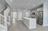 Modern open-concept kitchen with stainless steel appliances, elegant pendant lighting, and sleek hardwood floors, adjacent to a stylish staircase.