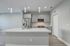 Contemporary kitchen with sleek gray cabinets, stainless steel appliances, and a sparkling quartz island featuring modern pendant lighting.