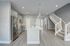 Modern kitchen design featuring sleek stainless steel appliances, elegant lighting, and a spacious island with quartz countertop, complemented by a stylish staircase.