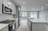 Modern kitchen with sleek stainless steel appliances, quartz countertops, and elegant pendant lighting leading into a bright, open-concept living space.