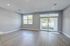 Bright living space with modern wood flooring, large windows, and sliding glass doors opening to a lush backyard.