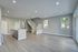 Bright open-plan living area with modern kitchen island, sleek wooden flooring, and elegant staircase leading to upper floor.