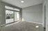 Bright, spacious room with plush carpet and large glass doors opening to a balcony view of lush palm trees.