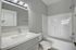 Modern bathroom showcasing a sleek vanity with a polished countertop, elegant mirror, and a stylish bathtub surrounded by soft gray walls.