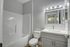 Modern bathroom with elegant lighting, sleek vanity, and spacious bathtub, complemented by soft gray tones for a relaxing ambiance.