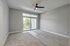 Bright and airy bedroom with plush carpets, modern ceiling fan, and large glass doors leading to a private balcony with lush views.