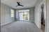 Bright and airy bedroom featuring plush carpet, modern ceiling fan, and large sliding glass doors opening to a serene view.