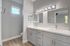 Luxurious bathroom featuring elegant double vanities, pristine mirrors, and modern lighting with sleek gray cabinetry.