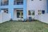 Bright view of a beautiful modern apartment exterior with blue and white design, private fenced yard, and lush green lawn.