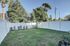 Charming backyard with lush green grass, bordered by a modern white fence and surrounded by vibrant trees, perfect for outdoor relaxation.