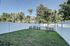 Private backyard oasis with lush greenery, white fenced perimeter, and vibrant garden touches, offering serene outdoor living.
