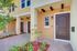 Charming townhouse entrance with elegant wooden door, inviting brick pathway, and lush greenery for a warm welcome.
