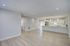 Bright and spacious open-concept living area featuring elegant wood flooring, modern kitchen with sleek white cabinetry, and ample natural light.