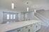 Modern open-concept living area with sleek kitchen island, elegant pendant lighting, and inviting staircase leading to upper level.