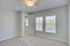 Bright, airy bedroom with plush carpet and large windows letting in natural light, offering a serene view.