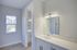 Bright and modern bathroom with sleek white cabinetry, elegant vanity mirror, and abundant natural light from a large window.
