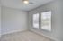 Bright and spacious bedroom with large windows and plush carpeting, perfect for relaxing and enjoying natural light.
