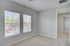 Bright and airy room with plush carpet, large windows, and fresh neutral decor, perfect for a cozy setup.