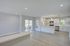 Elegant open-concept living room and kitchen with sleek white cabinetry, modern appliances, and abundant natural light.