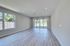 Bright and airy living area featuring modern wood flooring, large windows, and patio doors with a clear garden view, designed for comfortable and stylish living.