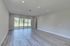 Bright, spacious living room with elegant wood flooring and large glass doors opening to a serene outdoor view.