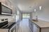 Modern kitchen with sleek stainless steel appliances, granite countertops, and spacious open layout leading to bright living area with large windows.