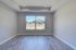 Bright and airy room with elegant laminate flooring, large window offering natural light and modern recessed lighting.