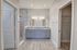 Elegant bathroom with dual sinks, sleek marble accents, and a spacious walk-in closet in a modern apartment.