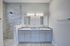 Elegant bathroom with dual sinks, marble shower, and modern design elements.