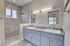 Elegant bathroom featuring dual sinks with granite countertops, modern mirrors, and a luxurious marble-tiled shower.