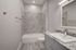 Elegant bathroom featuring a sleek vanity with a granite countertop, modern fixtures, and a marble-tiled shower area.