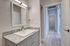 Modern bathroom with sleek granite countertop and elegant mirror, leading to a bright, spacious hallway.