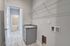 Bright and modern laundry room with chic light wood flooring, sleek granite countertop, and ample shelving space. Perfect blend of style and functionality.