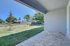 Inviting covered patio with paved floor opens to a spacious backyard, perfect for outdoor relaxation and entertainment.
