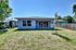 Charming modern home exterior with spacious grassy yard, large windows, and bright blue sky.