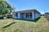 Lovely modern home with a spacious backyard, large windows, and a charming patio, perfect for outdoor relaxation.