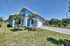 Charming modern home with sleek blue accents and palm trees, nestled in a lush green landscape, featuring a spacious driveway and manicured lawn.