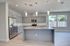 Contemporary kitchen with sleek gray cabinetry, stainless steel appliances, a marble countertop island, and modern pendant lighting.