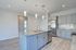Modern kitchen with elegant gray cabinetry, granite countertops, and stainless steel appliances under chic pendant lighting.