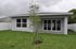 Charming modern home exterior with a lush green backyard and sleek patio doors, perfect for relaxation and outdoor gatherings.