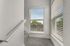 Bright and airy stairwell featuring modern carpeting and large windows with stylish blinds, offering a serene outdoor view.