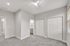 Modern bedroom with plush carpet, stylish ceiling fan, and ample closet space. Abundant natural light filters through large window blinds for a bright, inviting atmosphere.