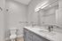 Modern bathroom with sleek marble countertop, stylish double sink, elegant gray cabinetry, and luxurious lighting.