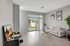 Bright modern living room with sleek decor, featuring a cozy sofa, elegant glass coffee table, and a view of the lush garden through large windows.