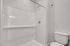 Contemporary bathroom featuring a sleek white shower with subway tile design and a pristine toilet, offering a clean and modern look.