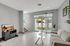 Modern living room with elegant decor, featuring a sleek gray sofa, a glass coffee table, and large sliding doors leading to a lush garden view.